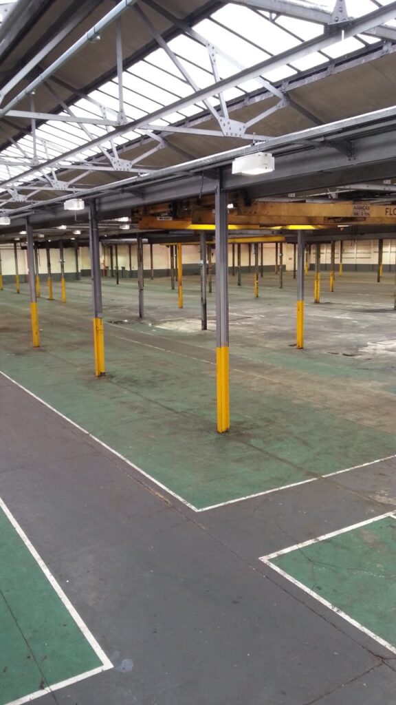 Empty industrial warehouse interior with metal beams and marked floor, showcasing spacious storage potential.
